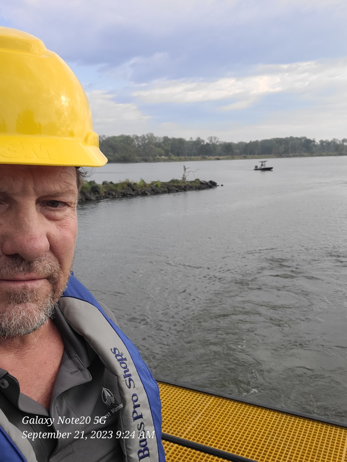 Kevin Mudd conducting marine field work wearing hard hat and personal flotation device